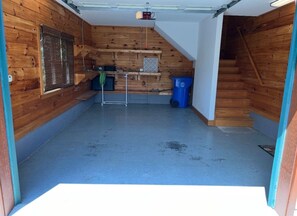 A room with wooden walls, a concrete floor, a metal rack, a blue trash bin, and a staircase leading to another level. - Chestnut Lodge-Fantastic Cabin! Easy Access, Views (Maggie Valley)