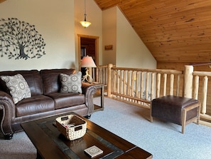 A cozy living room with a brown leather sofa, a wooden coffee table, and a decorative wall piece. - Chestnut Lodge-Fantastic Cabin! Easy Access, Views (Maggie Valley)