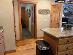 A kitchen with wooden cabinets, a granite countertop, a trash bin, and a sign on the wall. - Chestnut Lodge-Fantastic Cabin! Easy Access, Views (Maggie Valley)