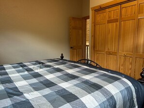 A bedroom with a bed, wooden wardrobe, and a door. - Chestnut Lodge-Fantastic Cabin! Easy Access, Views (Maggie Valley)