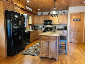 A kitchen with wooden cabinets, a black refrigerator, a microwave, and a coffee maker. - Chestnut Lodge-Fantastic Cabin! Easy Access, Views (Maggie Valley)