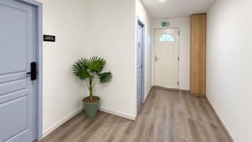 A hallway with a potted plant, a door with a sign, and a wooden panel.