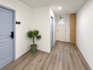 Un pasillo con una planta en maceta, una puerta con un letrero y un panel de madera.