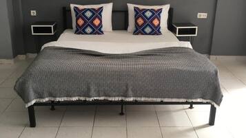 Un dormitorio con una cama, dos mesitas de noche, una colcha estampada y dos cuadros en la pared.