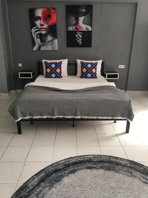Un dormitorio con una cama, dos mesitas de noche, una colcha estampada y dos cuadros en la pared.