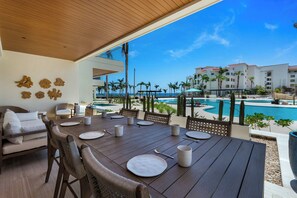 A dining area with a view of a pool and resort buildings. - 2BR Beachfront Condo With Pool Access & Terrace ! (San José del Cabo)