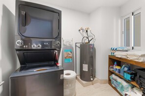 A compact laundry room with a washing machine, a dryer, and a water heater. - 2BR Beachfront Condo With Pool Access & Terrace ! (San José del Cabo)