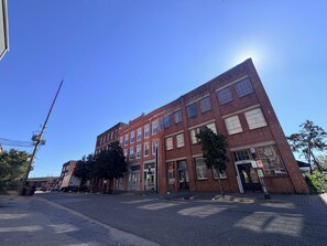 A multi-story brick building with a flat facade, large windows, and a visible entrance. - Soothing 1-bedroom apartment with AC in Birmingham (Birmingham)