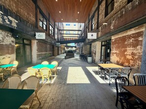 An indoor courtyard with brick walls, tables, and chairs arranged for dining. - Soothing 1-bedroom apartment with AC in Birmingham (Birmingham)