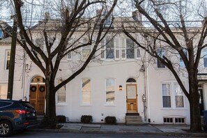 A row of white townhouses with arched doorways and a small front porch. - The Sycamore Downtown Modern Home (Lancaster)