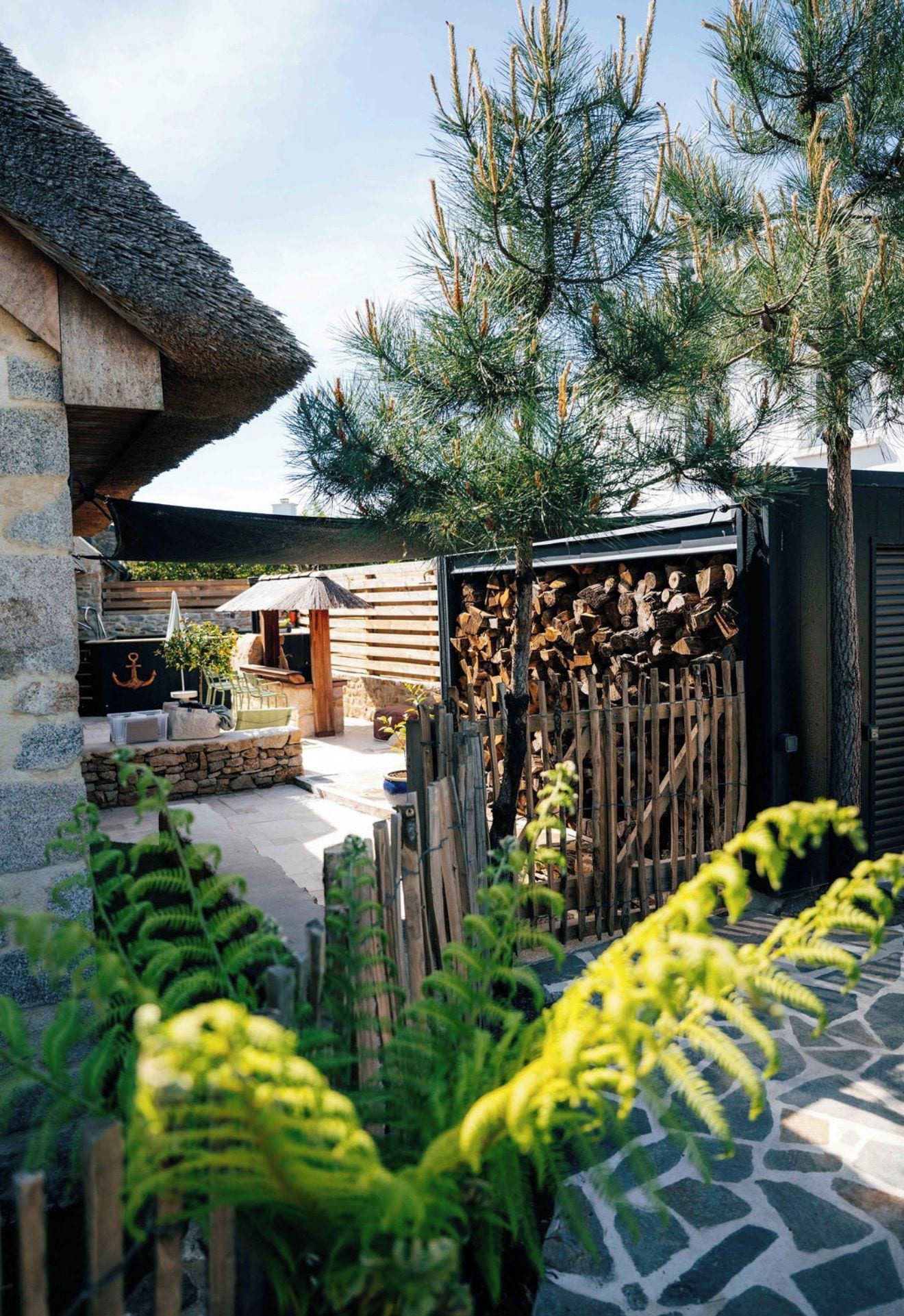 Un espace patio doté d’un sol en pierre, de mobilier d’extérieur, d’une clôture en bois et d’une pile de bois de chauffage.
