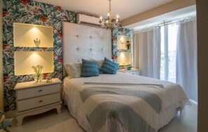 Ein Schlafzimmer mit einem großen Bett, einem Nachttisch, einer Kommode und einem Kronleuchter.