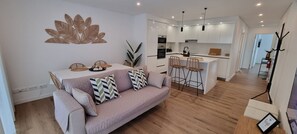 A modern living room with a sofa, a dining table, and a kitchen area with bar stools. - Ondas Beach House
Designed for your natural living a few steps from the beach (Monte Gordo)
