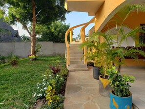 A modern building with a curved staircase, stone pathway, and potted plants. - Bella Breeze2 - Diani Beach, Kenya (Diani Beach)