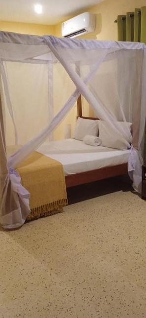 A single bed with a canopy, a bedside table, and a wall-mounted air conditioner. - Bella Breeze2 - Diani Beach, Kenya (Diani Beach)