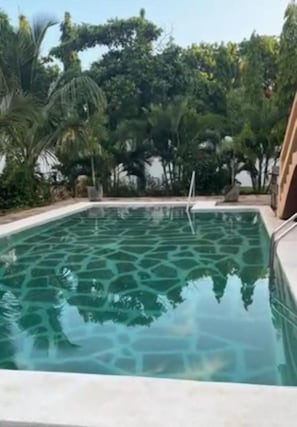 A swimming pool with a stone pattern on the bottom, surrounded by lush greenery and a clear sky. - Bella Breeze2 - Diani Beach, Kenya (Diani Beach)