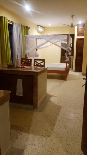 A room with a bed, a small table, and a ceiling fan. - Bella Breeze2 - Diani Beach, Kenya (Diani Beach)