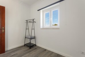 Une pièce avec une porte en bois, une étagère en métal noir et une fenêtre donnant sur le ciel.