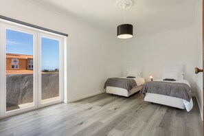 A room with two beds, a ceiling light, and a view through a sliding door to the outside. - Villa 'Bekas House' with private garden, balcony and Wi-Fi (Usseira)