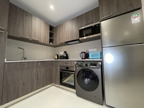 A modern kitchen with built-in appliances, including a washing machine, microwave, and refrigerator. - Luxurious 1-bedroom apartment Airport Residential (Accra)