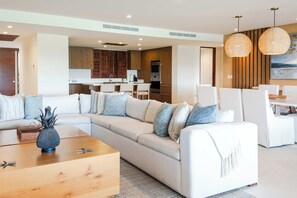 Ein modernes Wohnzimmer mit einer Eckcouch, einem Holztisch und einem Essbereich mit weißen Stühlen.