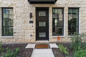 A stone building with a black door, numbered 239, and a doormat with a message. - Downtown Round Rock, Steps to Main St (Round Rock)