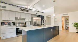 A modern kitchen with white cabinets, stainless steel appliances, and a blue accent wall. - Private Pool Oasis | Near Tempe Diablo Stadium (Phoenix)