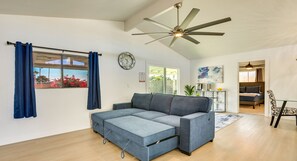 A modern living room with a sectional sofa, a ceiling fan, a clock, and a view of the outdoors. - Private Pool Oasis | Near Tempe Diablo Stadium (Phoenix)