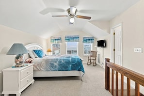 Une chambre à coucher avec un lit, une table de chevet, une lampe et un ventilateur de plafond.