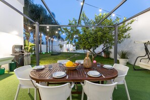 An outdoor dining area with a wooden table, white wicker chairs, and string lights. - Villa Escondida - Taviano (Taviano)