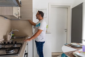 Uma pessoa em uma cozinha com fogão, pia e armários.