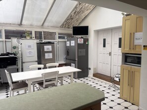 Eine kompakte Küche mit Esstisch, Stühlen, Kühlschrank, Mikrowelle und Fernseher.