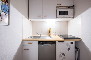 A compact kitchen with a microwave, dishwasher, and a sink with a wooden countertop. - Le Montagnard - Vue Mont Blanc - Pistes (Landry)