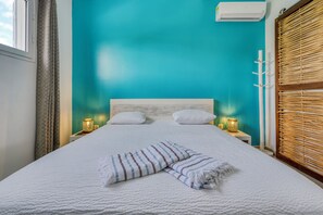 A bed with white bedding, two pillows, and a striped throw blanket. - Villa Corail - Piscine et vue mer - Clim (Le Robert)