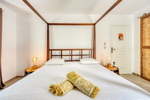 Ein Hotelzimmer mit einem großen Bett, einem Holzkopfstück, einem Nachttisch mit Lampe, einer Tür mit Schild und einem an der Wand befestigten Telefon.