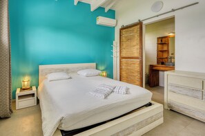 Une chambre à coucher avec un lit, des tables de chevet, une armoire et une salle de bain visible à travers une porte ouverte.
