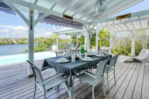 Un espace extérieur aménagé pour prendre les repas, avec vue sur la mer, un coin salon abrité et une piscine.