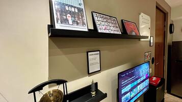 Una pared con cuadros enmarcados, un televisor mostrando una película y un letrero que indica la disponibilidad de WiFi.