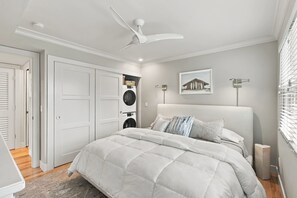 Een slaapkamer met een bed, een plafondventilator, een wandlamp en een ingelijste foto.