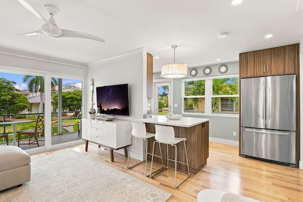 A modern kitchen with a large island, stainless steel appliances, and a TV mounted on the wall. - Downtown Naples Walkable Escape – Private Lanai, Steps to Beach & 5th Avenue (Naples)