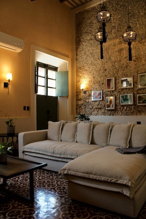 A living room with a sofa, a coffee table, and a patterned rug. There are wall-mounted lights and framed pictures on the wall. - Estrena casa boutique • Mérida Centro • 5 habs (Mérida)