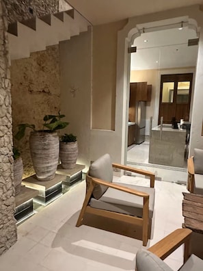 A modern interior with a stone wall, a wooden chair, and large potted plants. - Estrena casa boutique • Mérida Centro • 5 habs (Mérida)