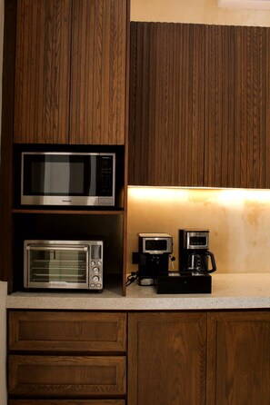 A kitchen with wooden cabinets, a microwave, a toaster oven, and a coffee maker. - Estrena casa boutique • Mérida Centro • 5 habs (Mérida)
