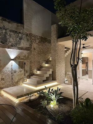 A modern outdoor staircase with stone walls and lighting, surrounded by plants and a tree. - Estrena casa boutique • Mérida Centro • 5 habs (Mérida)