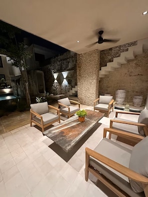 A modern outdoor seating area with a stone wall, a ceiling fan, and a staircase. - Estrena casa boutique • Mérida Centro • 5 habs (Mérida)
