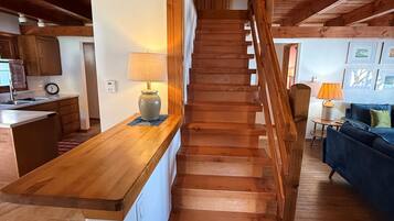 A wooden staircase leading to a second floor, with a kitchen area on the left and a living room on the right.