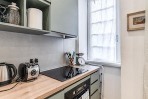 A kitchen with a wooden countertop, a kettle, a toaster, a scale, and a window with curtains. - Buccari Apartment - 3 Bedrooms with En-suite Bathrooms - Near the Vatican (Roma)