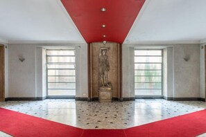 A lobby with a red carpet, a statue, and large windows. - Buccari Apartment - 3 Bedrooms with En-suite Bathrooms - Near the Vatican (Roma)