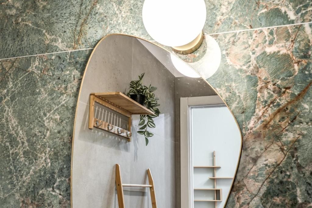 A bathroom with a marble wall, a wooden shelf with plants, a ladder, and a mirror.