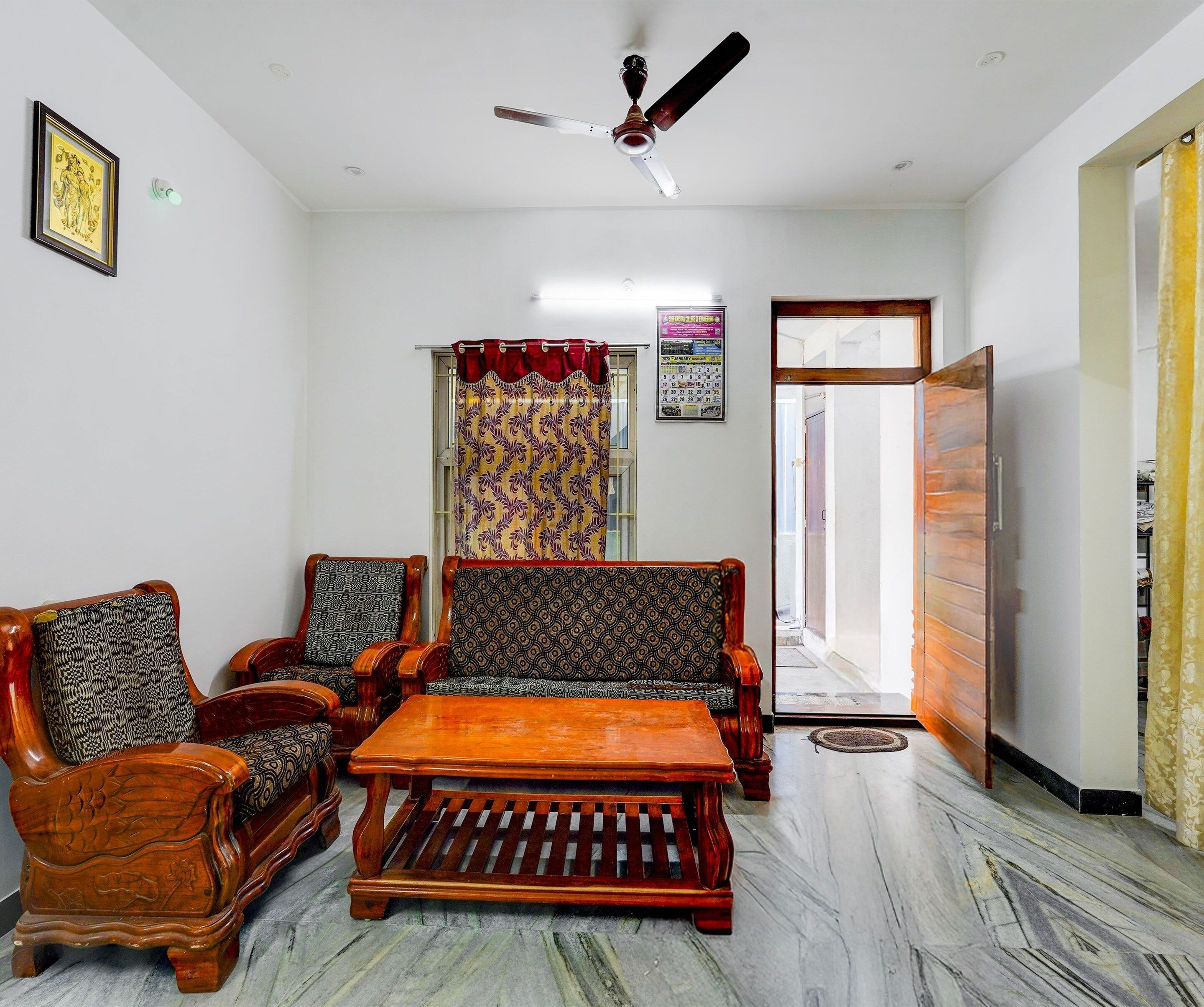 A room with a ceiling fan, patterned curtains, a wooden sofa, and a coffee table.